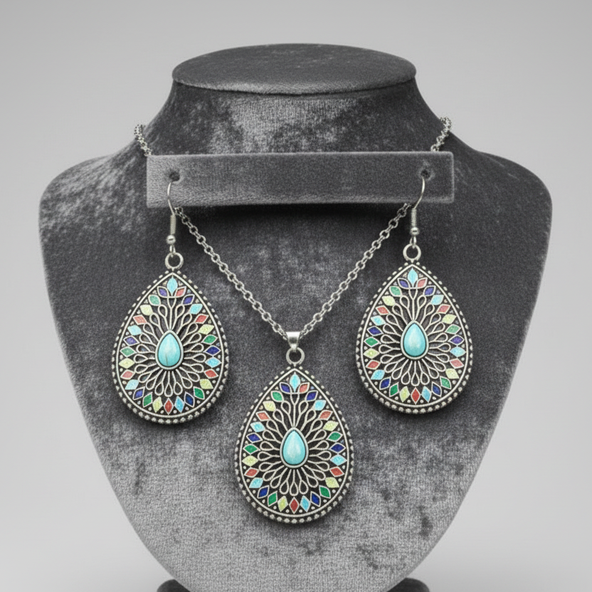 A set of bohemian style jewelry, including a necklace and a pair of earrings with a blue center and multicolored patterns around it, all in a teardrop shape design.