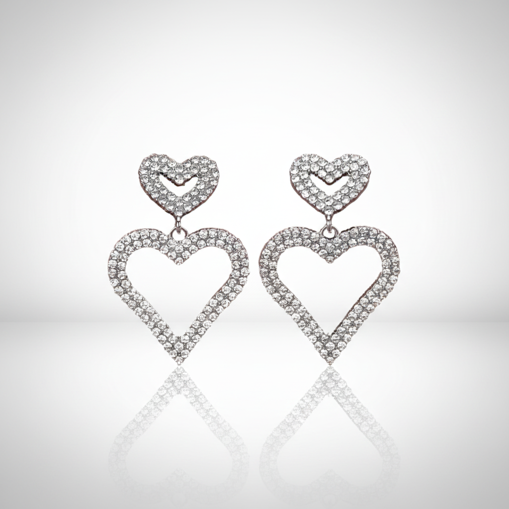 Heart-shaped earrings with diamond-like stones on a reflective surface