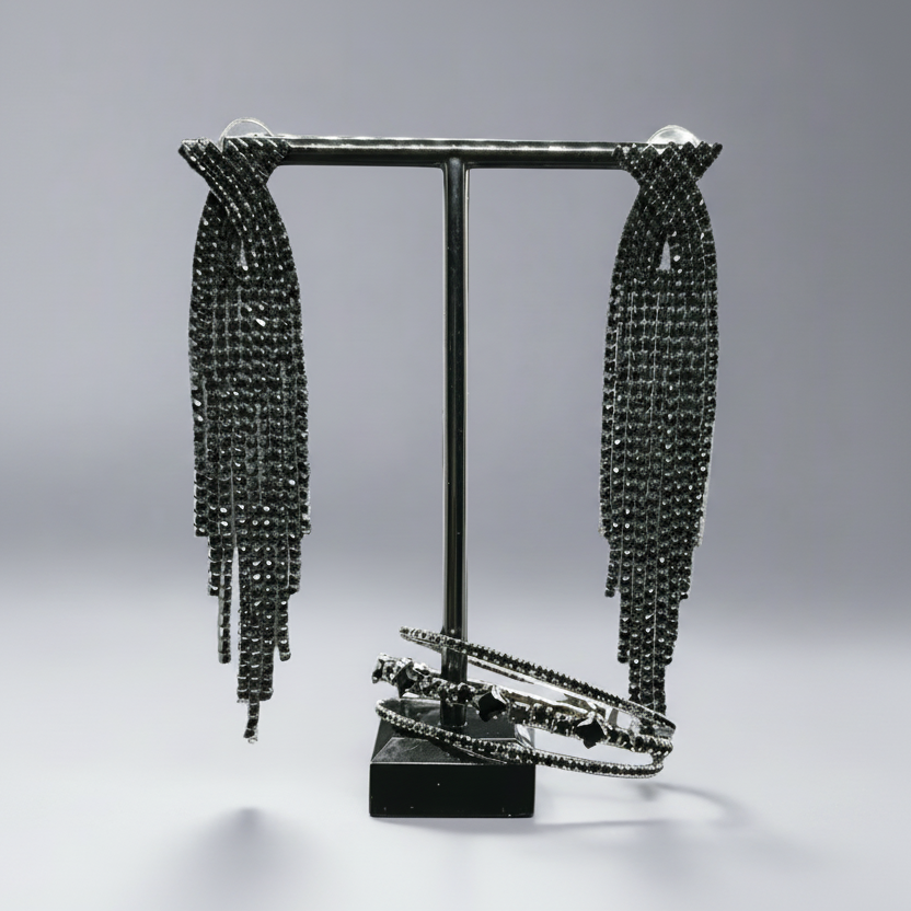 Black beaded earrings on a stand against a gray background