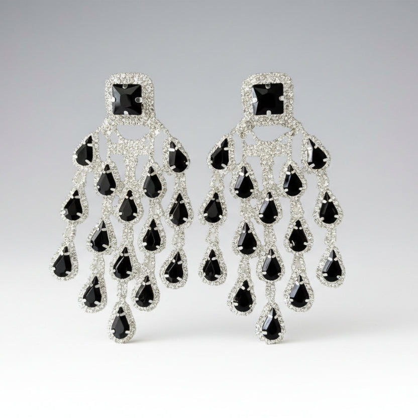 A pair of tassel earrings with black, clear, and silver components. The earrings feature a square stone with teardrop-shaped tassels hanging below, accented with clear rhinestones.