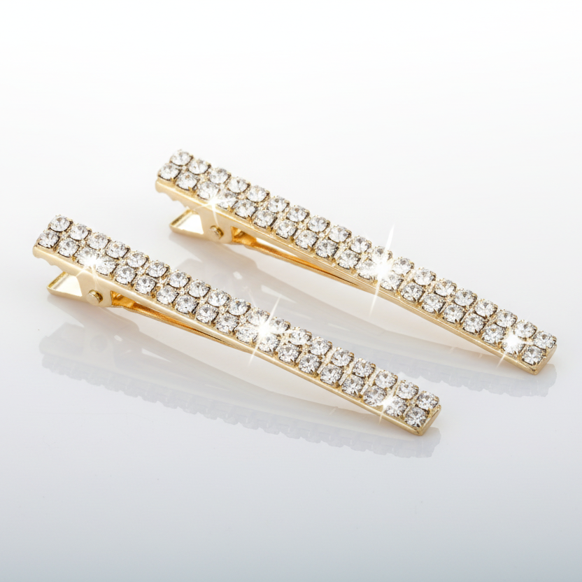 Two gold hair clips with crystal stones on a light gray background