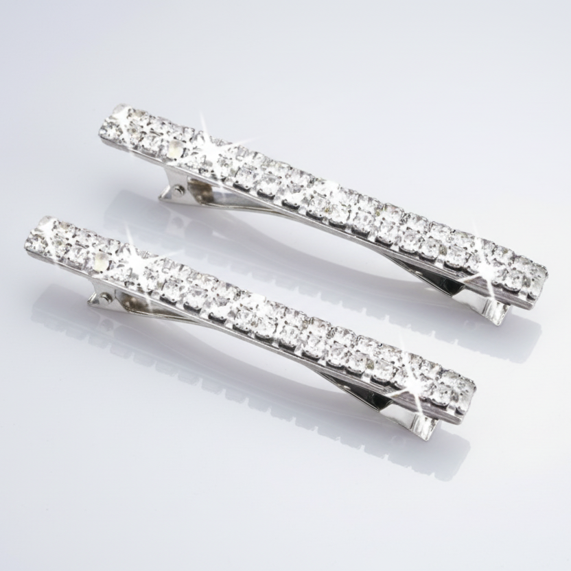 Two silver hair clips with clear gemstones on a light gray background