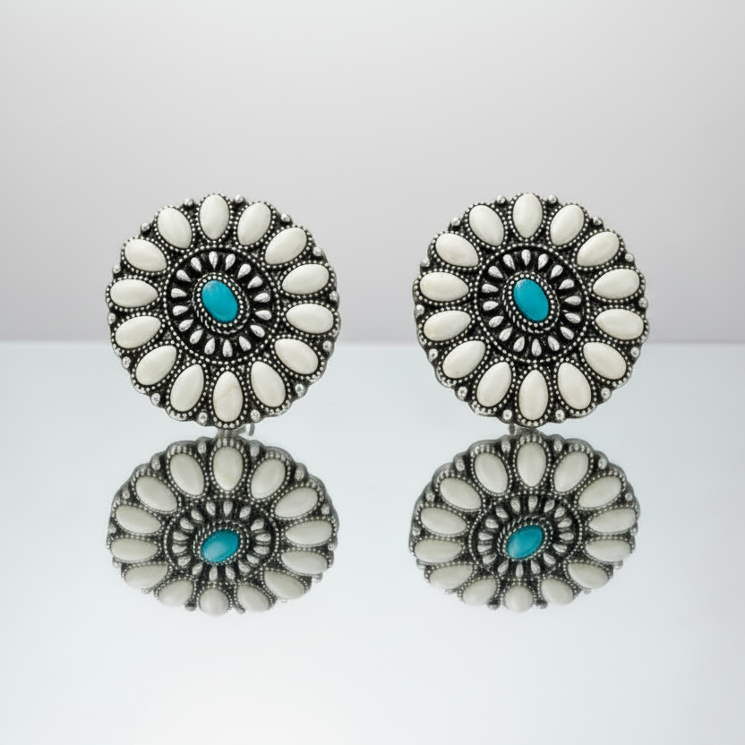 Pair of earrings with white and turquoise design on a reflective surface.