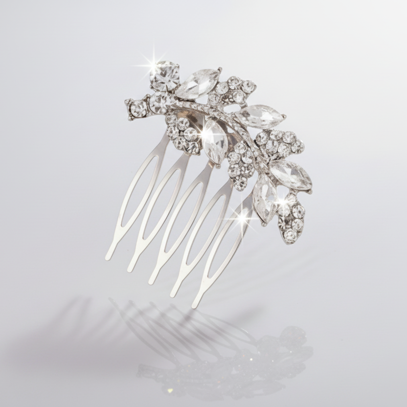 Silver hair comb with leaf-like design and clear stones on a light gray background