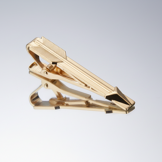 Gold tie clip on a light gray background