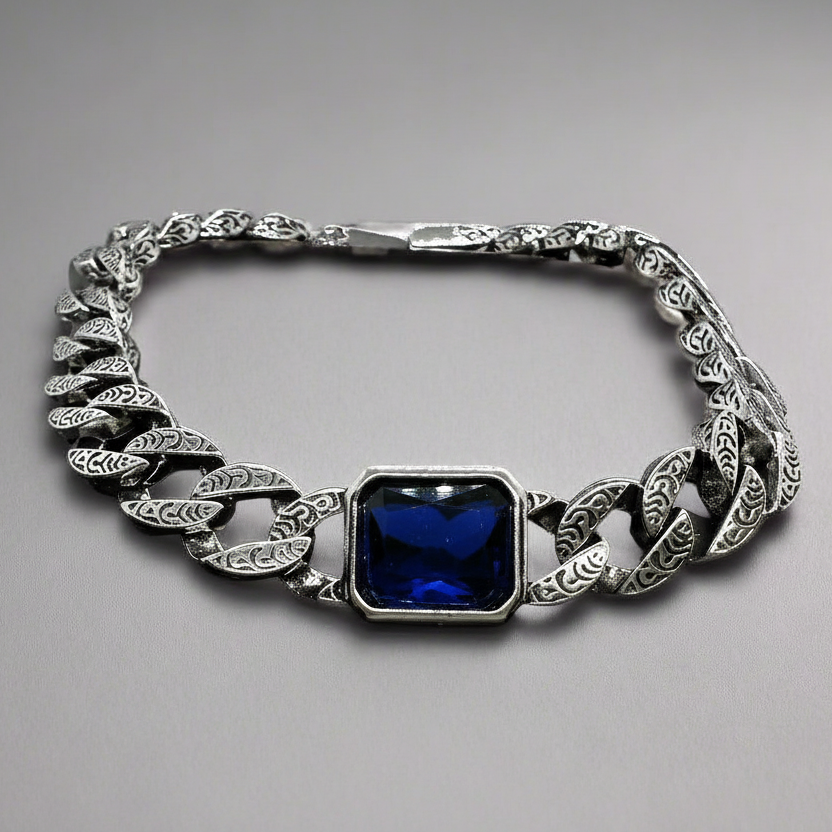 Silver chain bracelet with a blue gemstone on a gray background