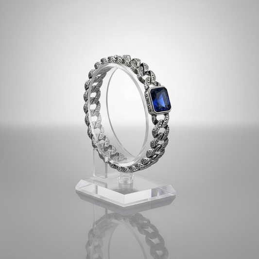 Silver chain bracelet with a blue gemstone on a gray background