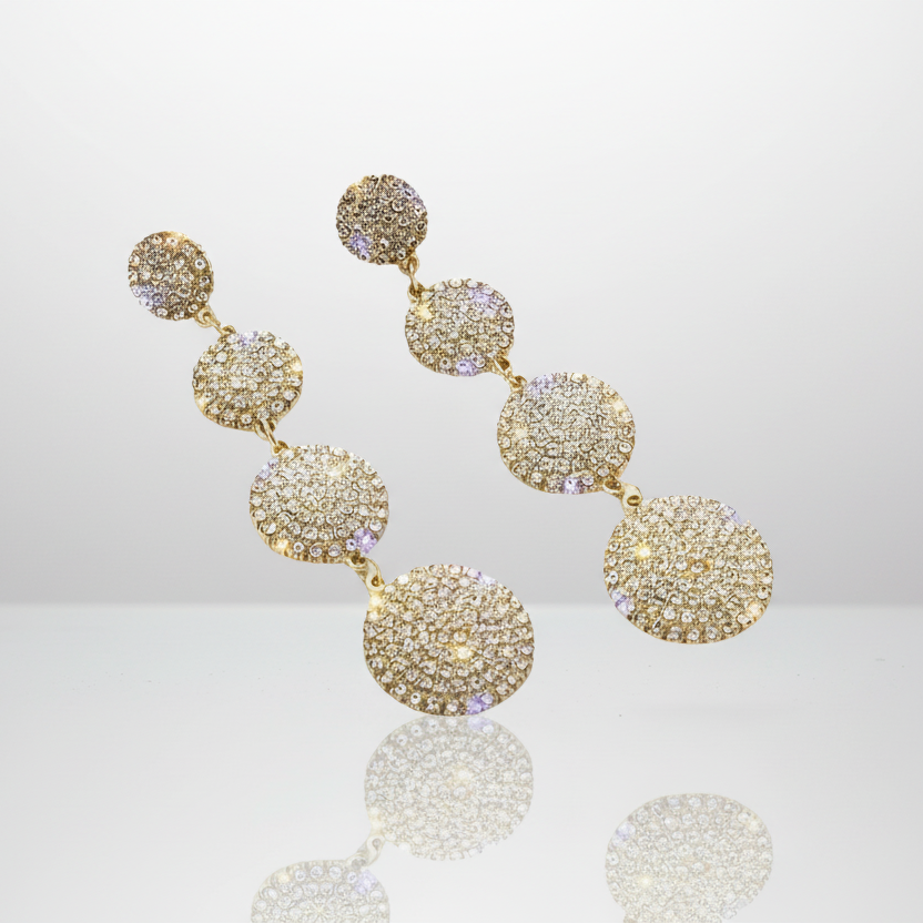 Gold earrings with multiple round pendants on a reflective surface.