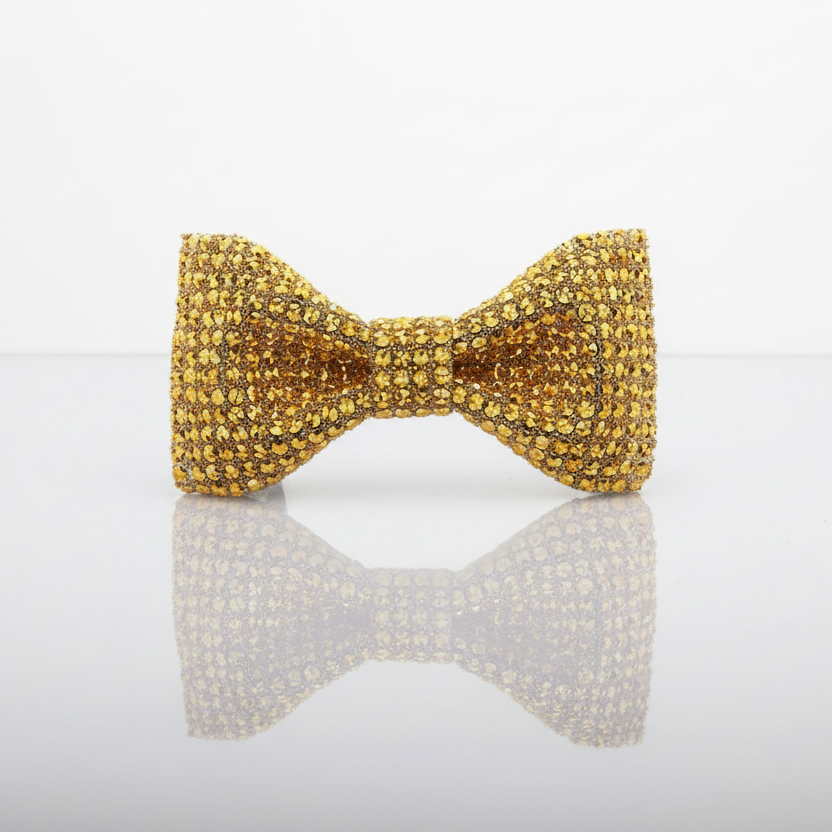 Gold bow-shaped object on a reflective surface with a white background