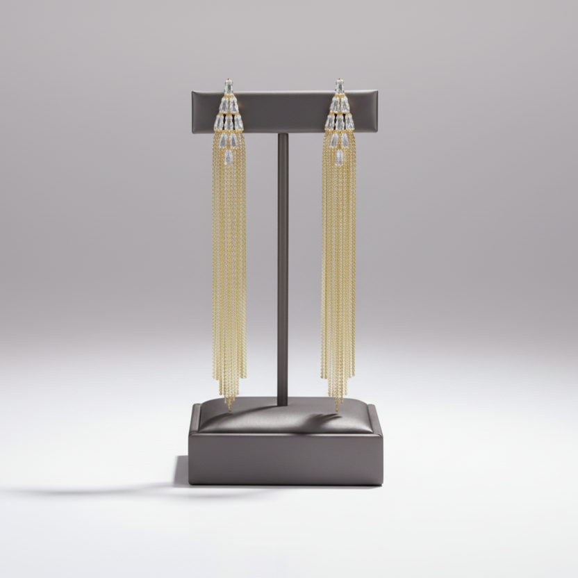 Gold chain tassel earrings on a gray stand against a light gray background