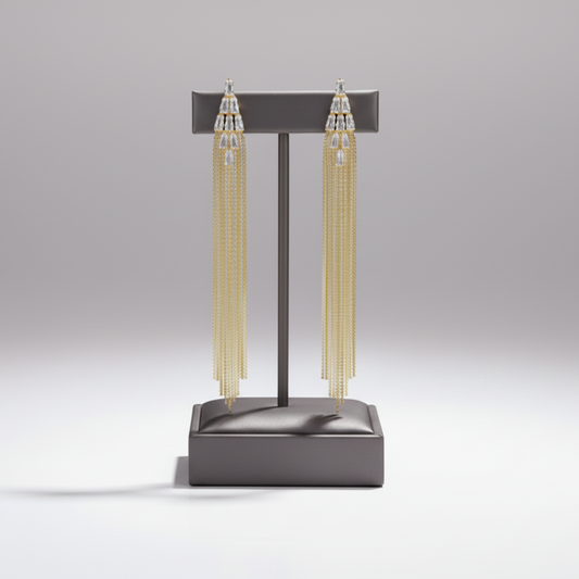 Gold chain tassel earrings on a gray stand against a light gray background