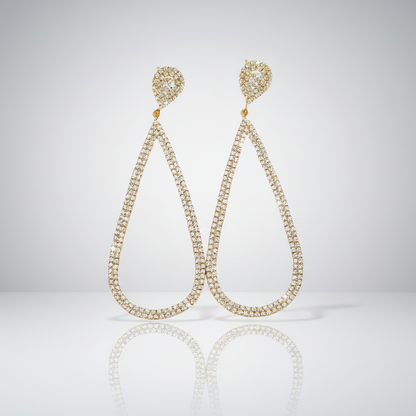 Pair of gold teardrop earrings on a reflective surface with a light gray background