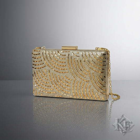 A gold rectangular clutch bag with an intricate scalloped beaded pattern, a gold clasp, and a gold chain strap, displayed on a reflective gray surface against a gradient gray background.