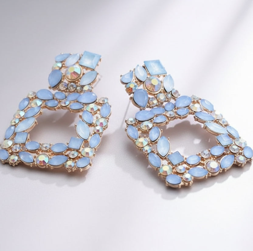 Pair of decorative earrings with blue gemstones on a white background