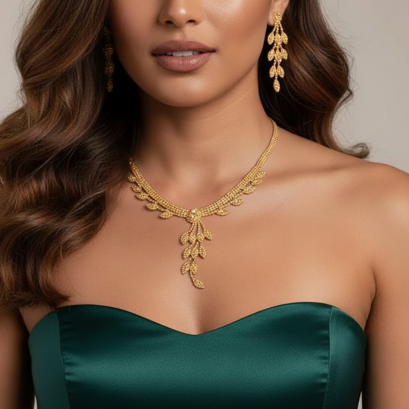 Woman wearing a gold and rhinestone necklace and earrings with a green dress on a neutral background