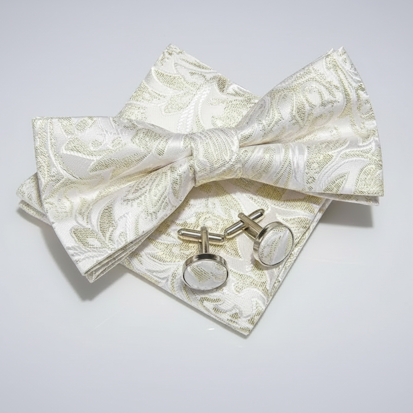 Set of white bow tie, pocket square, and cufflinks with gold pattern on a light gray background