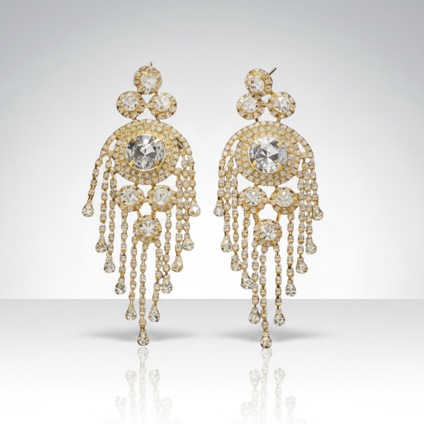 Pair of gold earrings with clear gemstones on a light gray background
