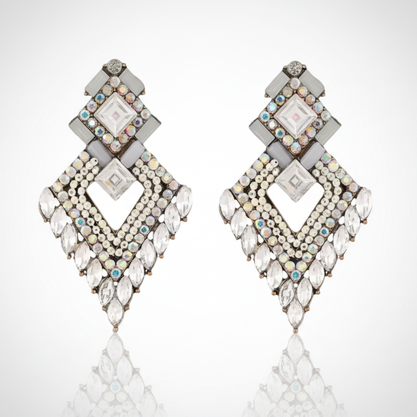 Pair of diamond-shaped earrings with gemstones on a reflective surface.