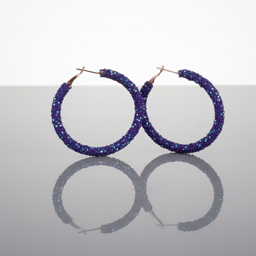A pair of dark purple rhinestone chip and sequin hoop earrings with gold-tone hooks.