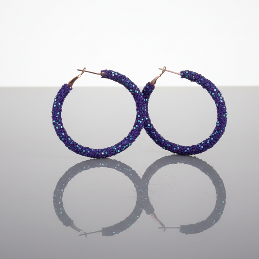 A pair of dark purple rhinestone chip and sequin hoop earrings with gold-tone hooks.