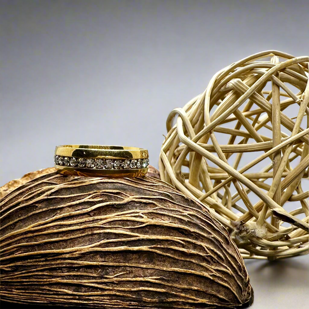 Gold ring with faux diamonds on a textured surface next to a woven ball