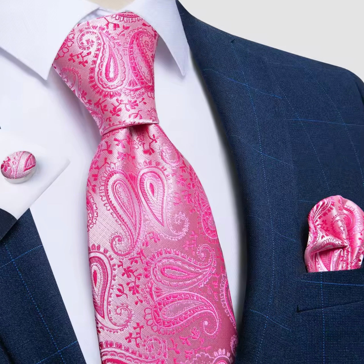 Pink paisley tie with matching pocket square and cufflinks on a navy suit.