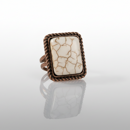 Ring with a rectangular stone and bronze frame on a light gray background