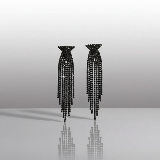 Pair of black beaded earrings on a reflective surface with a gradient background