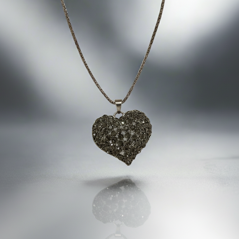 Heart-shaped diamond pendant on a chain against a blurred background