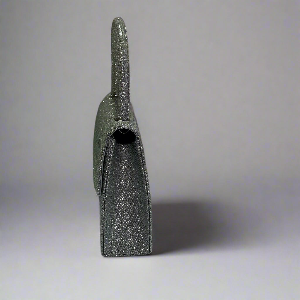 Silver glitter handbag on a white surface with a gray background