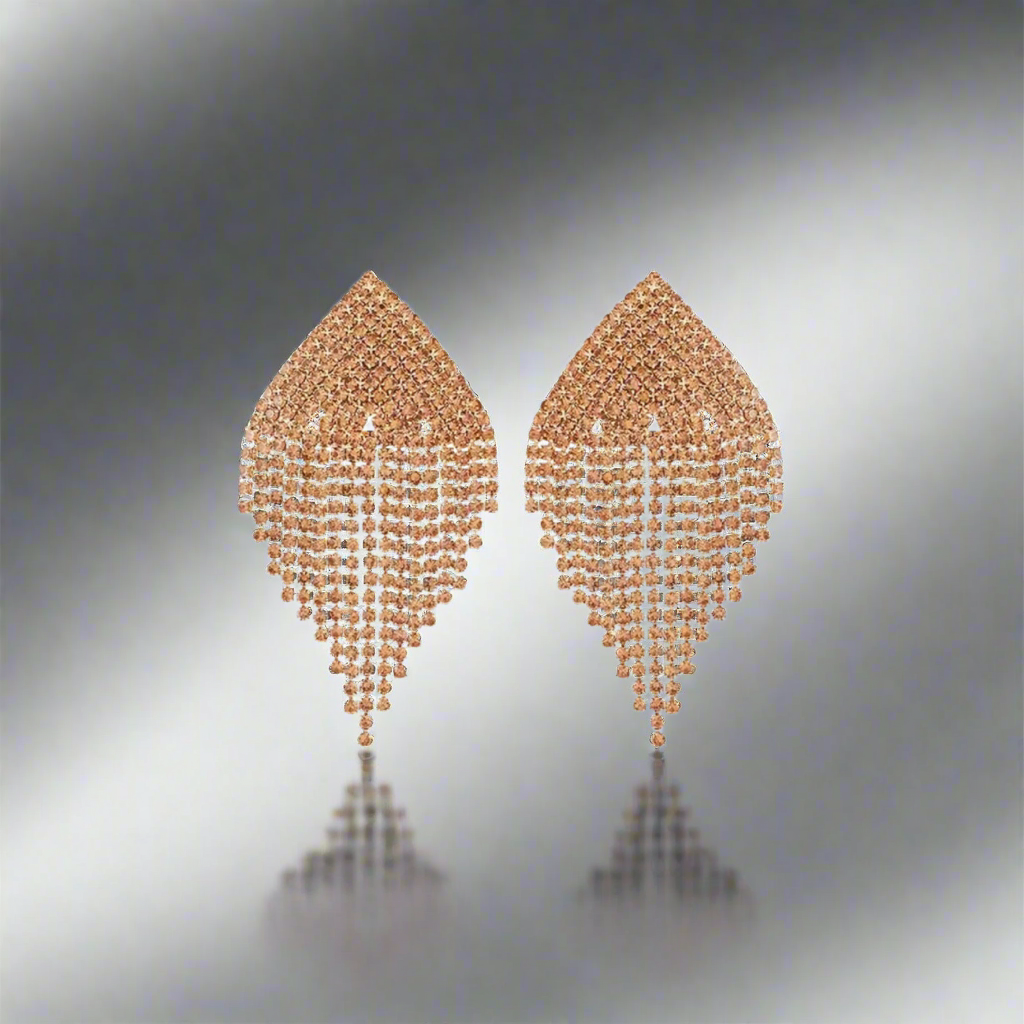 Pair of champagne gold earrings on a reflective surface with a gradient background