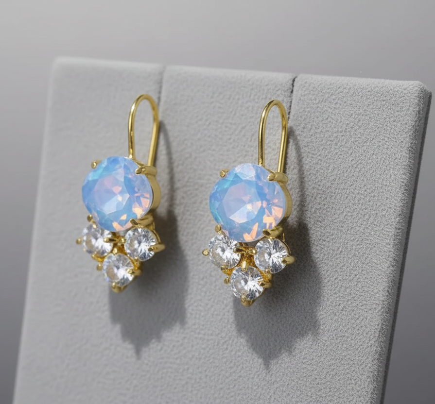 Gold earrings with blue gemstones on a gray surface