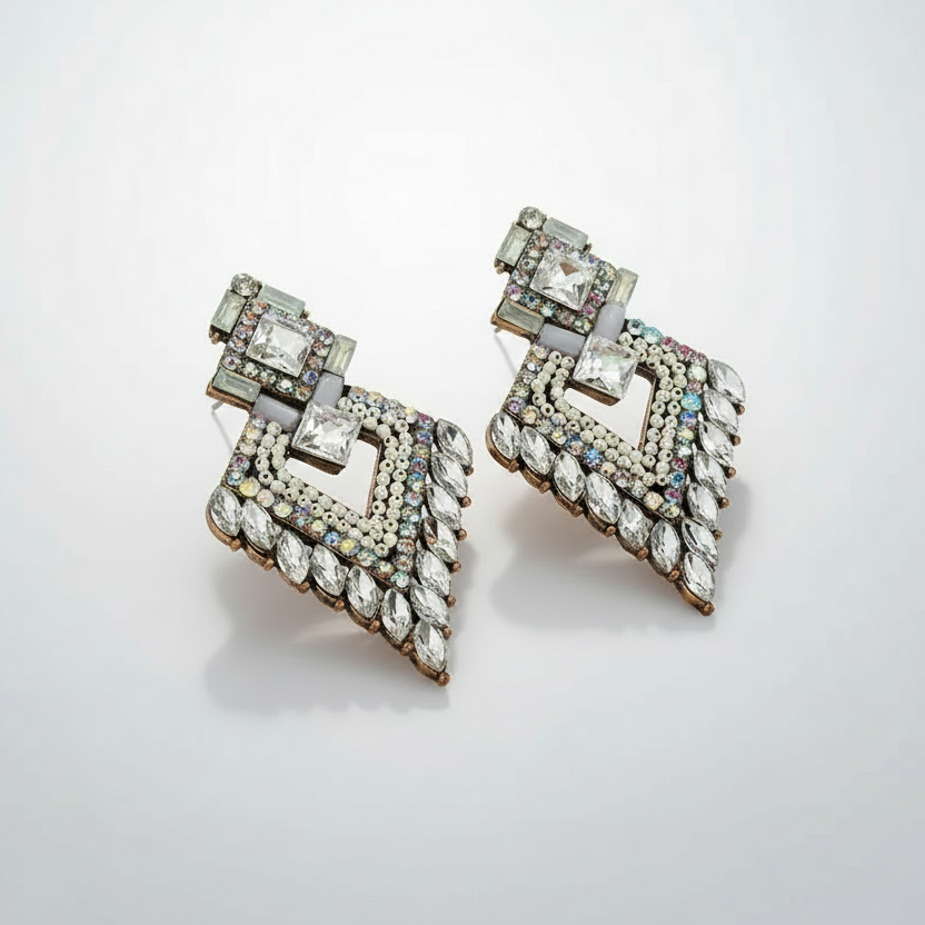 Pair of ornate earrings with gemstones on a light gray background