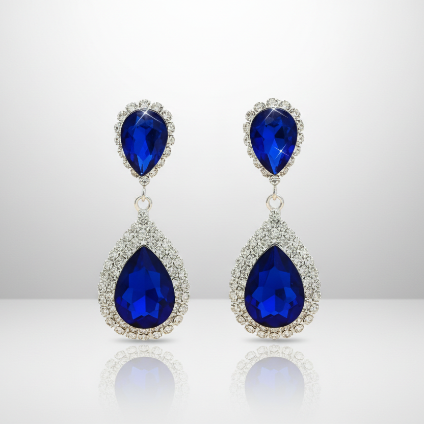 Pair of blue teardrop earrings on a reflective surface with a light gray background