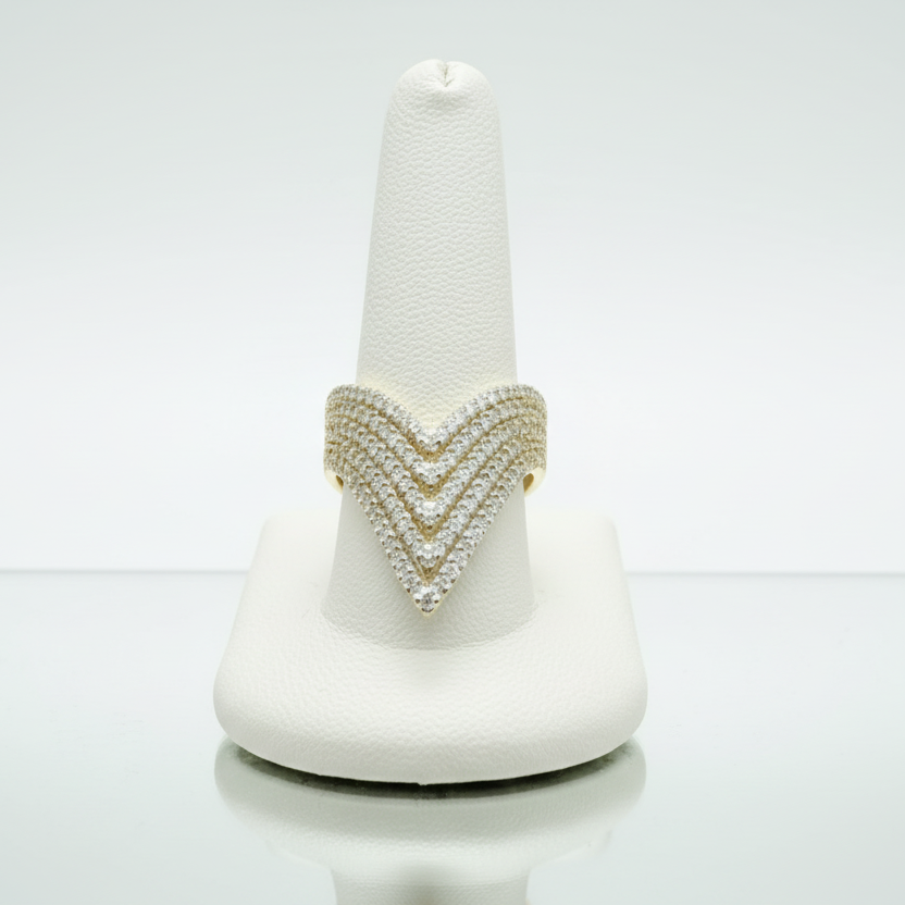 Gold ring with a chevron pattern on a white stand against a white background