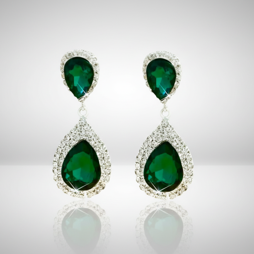Pair of emerald green teardrop earrings on a reflective surface with a light gray background