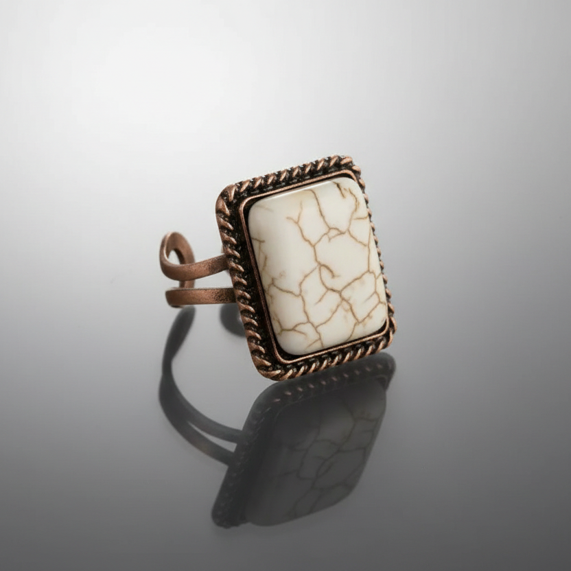 Ring with a textured stone and bronze frame on a reflective surface