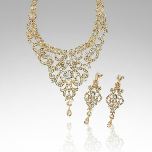 Gold necklace and earrings set on a reflective surface with a gray background