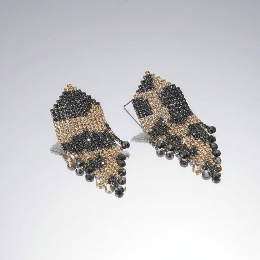 Pair of beaded earrings with black and gold design on a light gray background