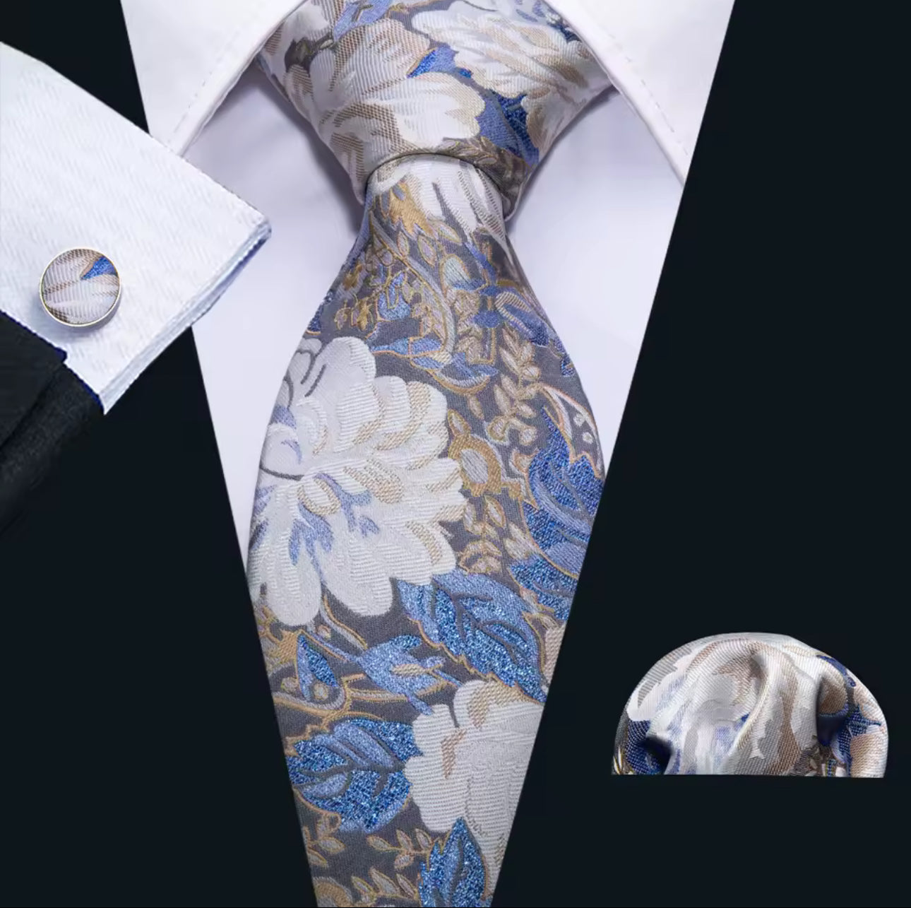 Floral patterned tie with matching pocket square and cufflinks on a white shirt.