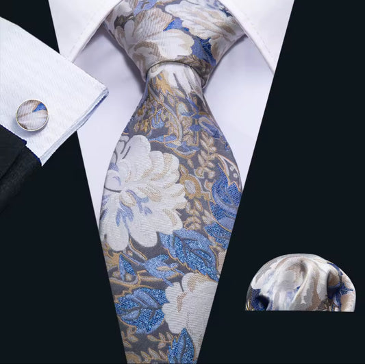 Floral patterned tie with matching pocket square and cufflinks on a white shirt.
