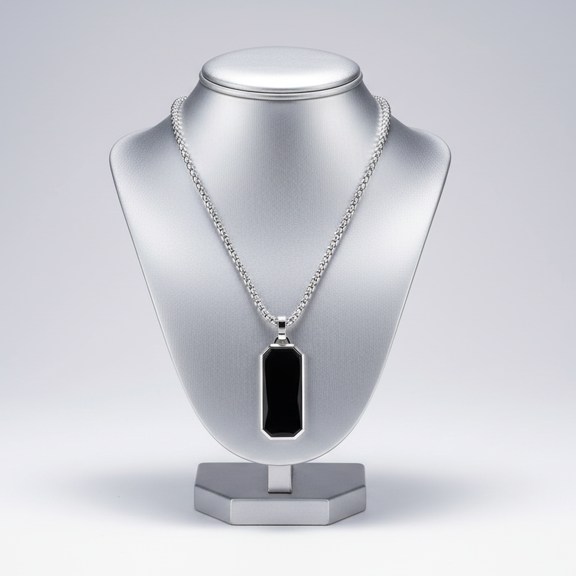 Silver necklace with a black pendant on a silver mannequin bust against a light gray background