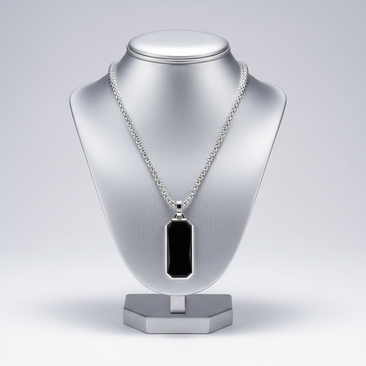 Silver necklace with a black pendant on a silver mannequin bust against a light gray background