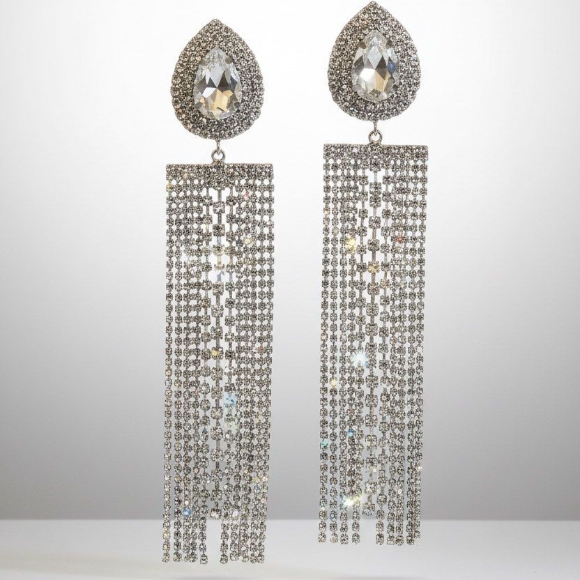 Pair of silver teardrop earrings with dangling crystals on a light gray background