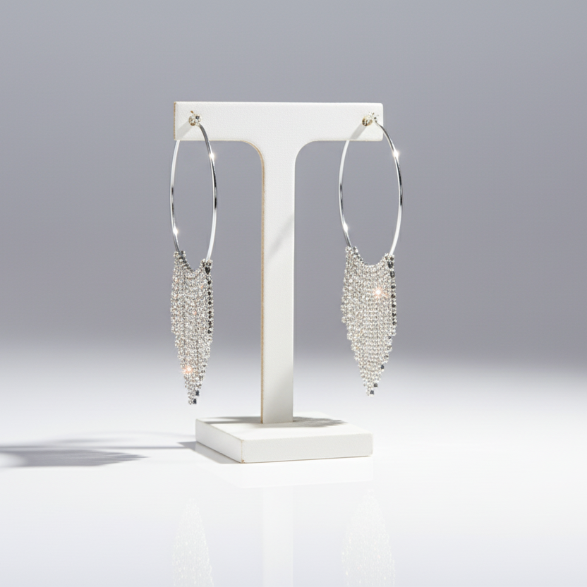 Silver hoop earrings on a white stand against a gray background