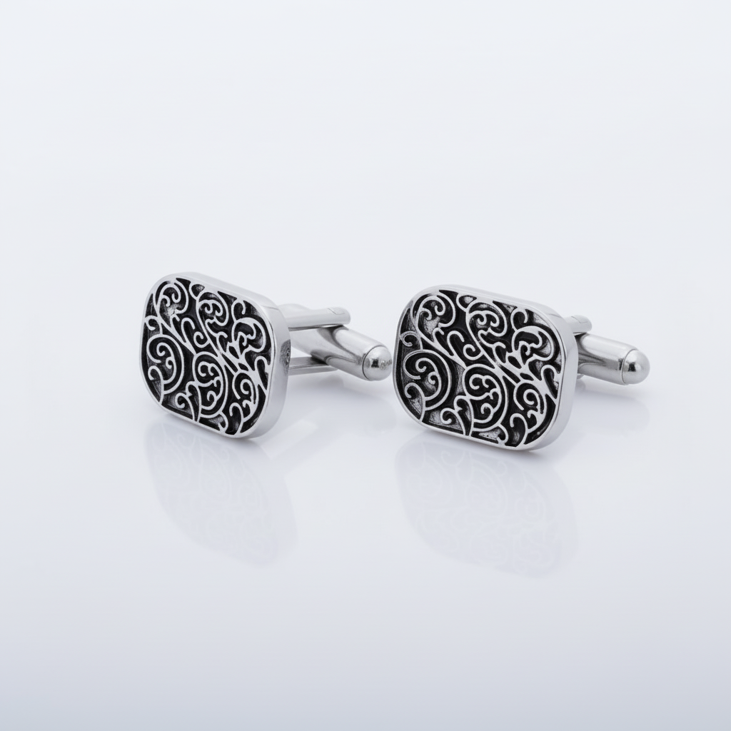A pair of silver cufflinks with a scroll design.