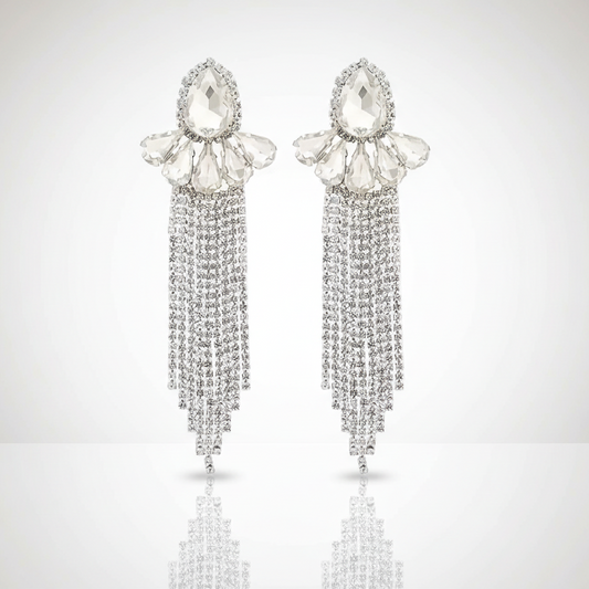 Pair of silver earrings with teardrop-shaped crystals and dangling chains on a light gray background