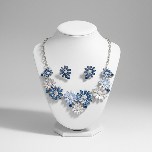 A jewelry set consisting of a necklace and a pair of earrings with metallic blue and white flowers on a silver-colored chain.
