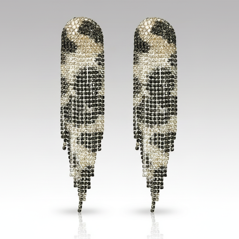 Pair of feather-shaped earrings with black and clear gemstones on a gray background