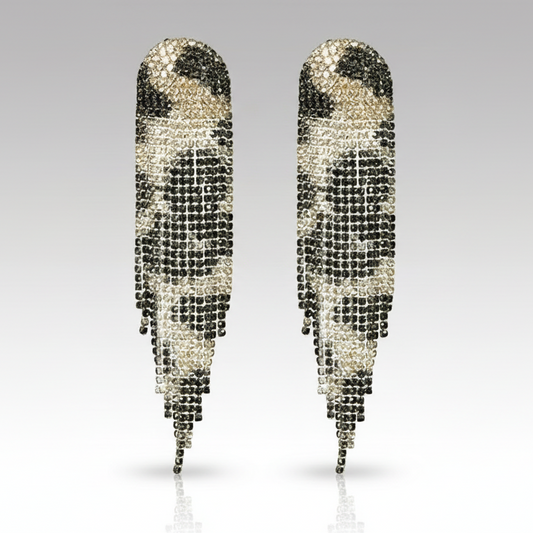 Pair of feather-shaped earrings with black and clear gemstones on a gray background